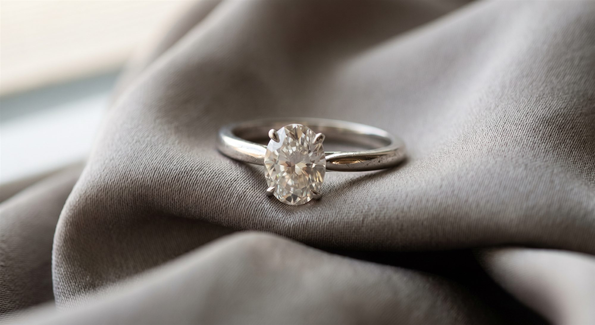 Oval diamond solitaire ring on satin